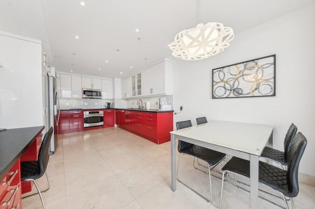 kitchen featuring white cabinetry, hanging light fixtures, stainless steel appliances, backsplash, and light tile patterned floors