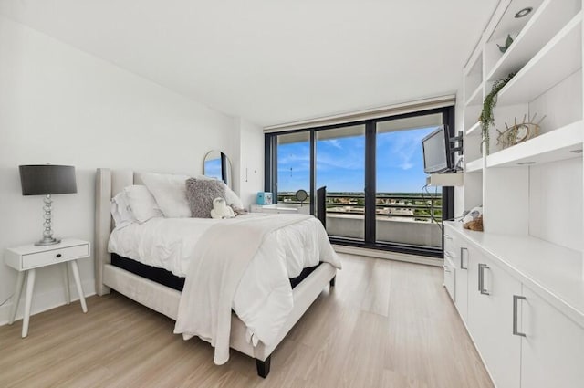 bedroom with floor to ceiling windows and light wood-type flooring