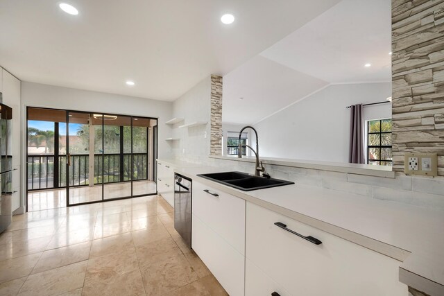 kitchen with decorative backsplash, white cabinetry, stainless steel dishwasher, and sink