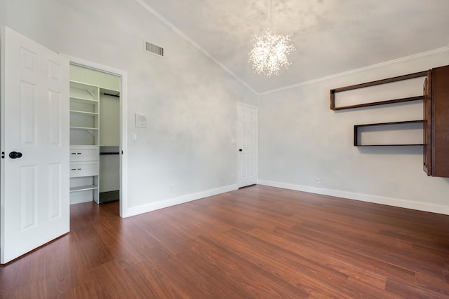 spare room featuring dark hardwood / wood-style flooring, lofted ceiling, crown molding, and an inviting chandelier