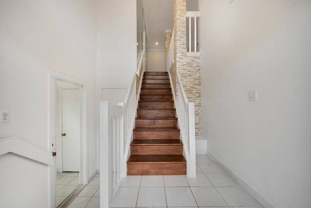 stairs with tile patterned floors and a high ceiling