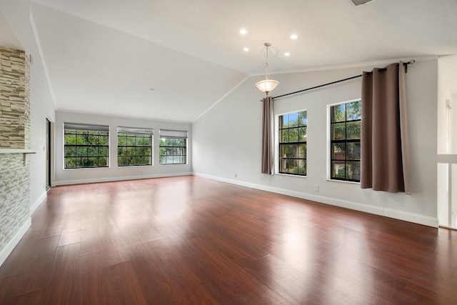 empty room with dark hardwood / wood-style flooring, plenty of natural light, a fireplace, and vaulted ceiling