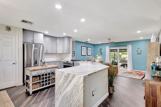 kitchen featuring gray cabinetry, dark hardwood / wood-style floors, light stone countertops, appliances with stainless steel finishes, and kitchen peninsula