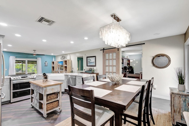 dining room with ceiling fan with notable chandelier, wood-type flooring, a barn door, and sink