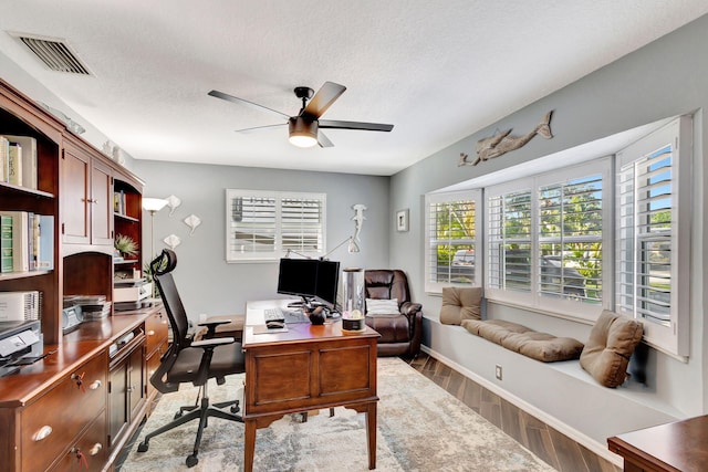 home office featuring hardwood / wood-style floors, ceiling fan, and a textured ceiling