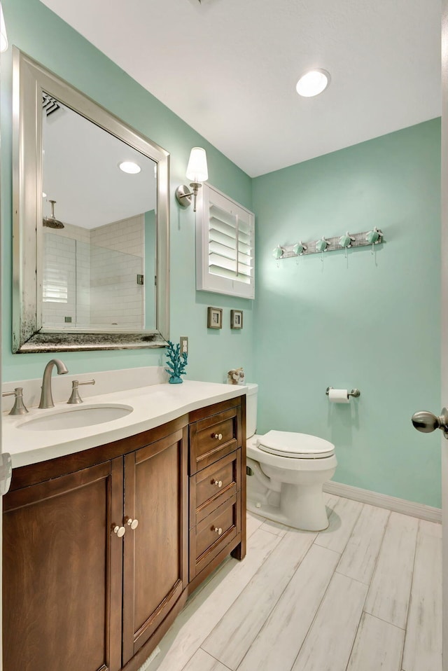 bathroom featuring a tile shower, vanity, toilet, and wood-type flooring