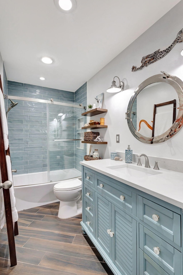 full bathroom featuring combined bath / shower with glass door, vanity, and toilet