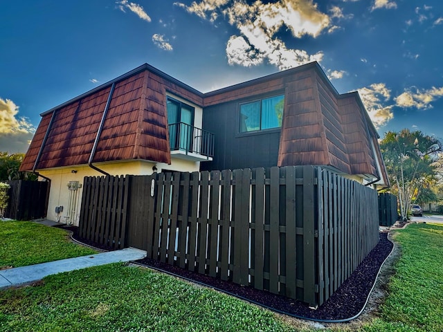 view of side of home with a yard and a balcony