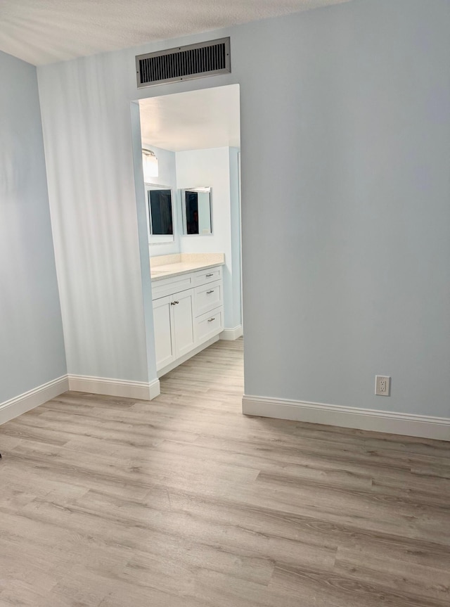 spare room with a textured ceiling and light wood-type flooring