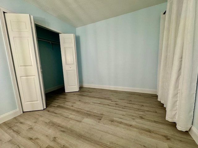 unfurnished bedroom with light wood-type flooring and a closet