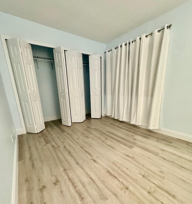 unfurnished bedroom featuring light hardwood / wood-style floors and multiple closets