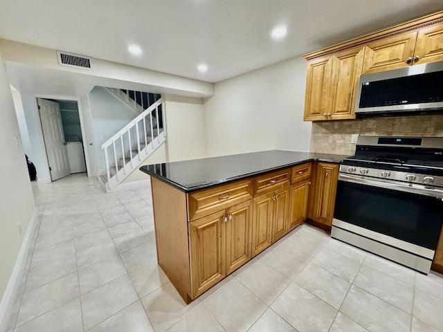 kitchen with stainless steel appliances, backsplash, kitchen peninsula, dark stone countertops, and light tile patterned floors