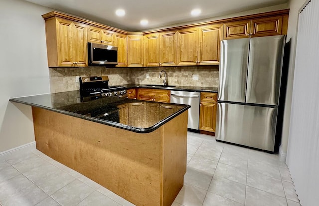 kitchen featuring decorative backsplash, dark stone countertops, sink, and stainless steel appliances