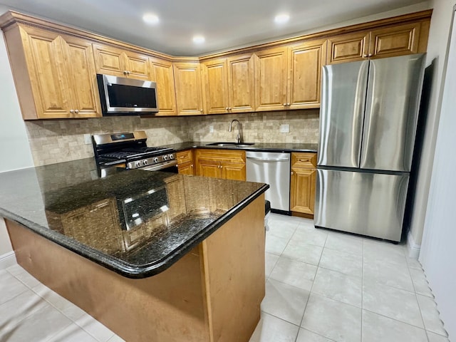 kitchen featuring sink, tasteful backsplash, kitchen peninsula, dark stone countertops, and appliances with stainless steel finishes