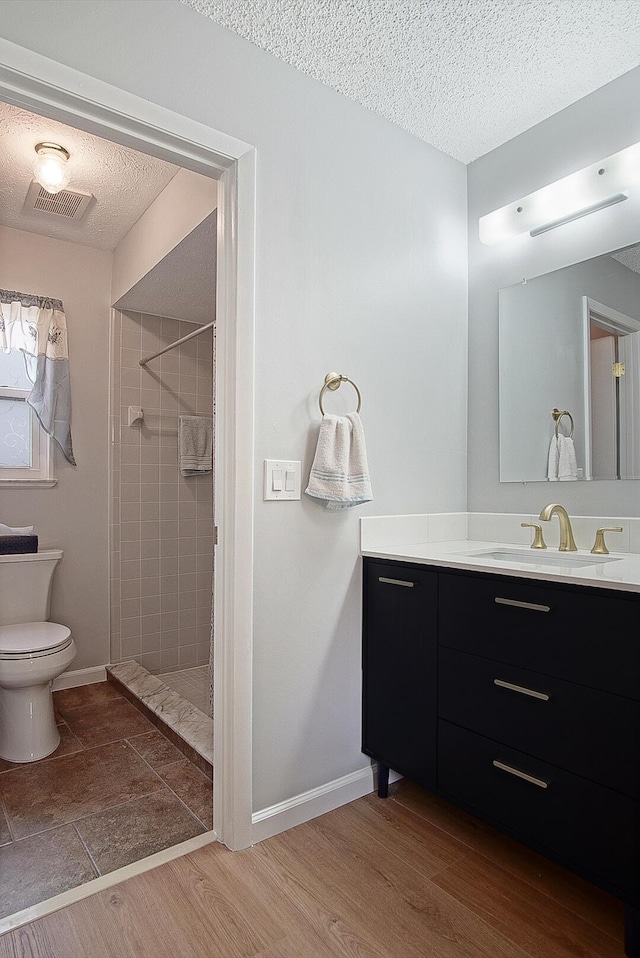 bathroom with tiled shower, vanity, a textured ceiling, and hardwood / wood-style flooring