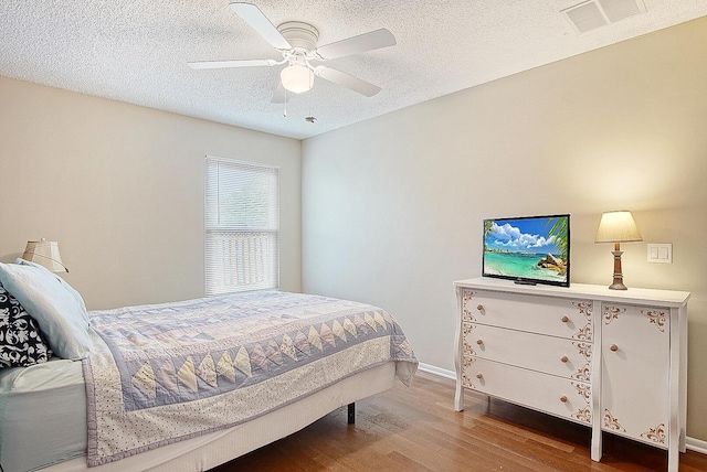 bedroom featuring hardwood / wood-style flooring, ceiling fan, and a textured ceiling