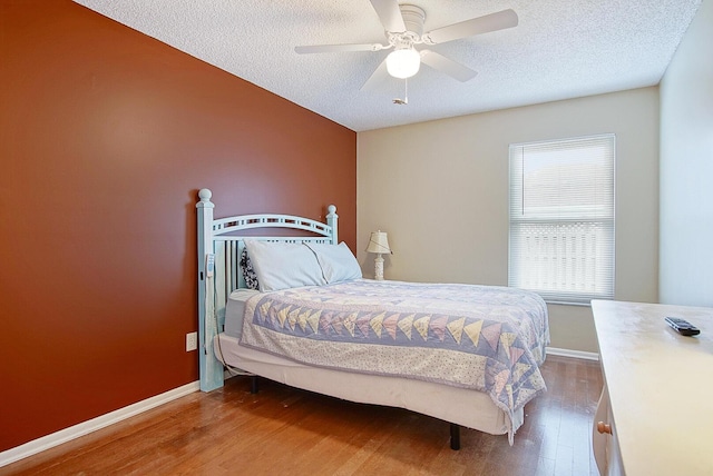 bedroom featuring ceiling fan, wood-type flooring, and a textured ceiling