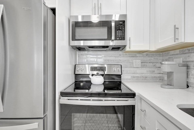 kitchen featuring tile patterned floors, decorative backsplash, white cabinetry, and appliances with stainless steel finishes