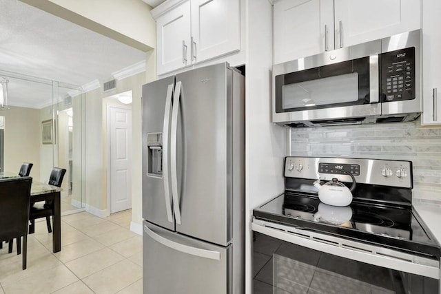 kitchen with stainless steel appliances, light tile patterned floors, tasteful backsplash, crown molding, and white cabinets