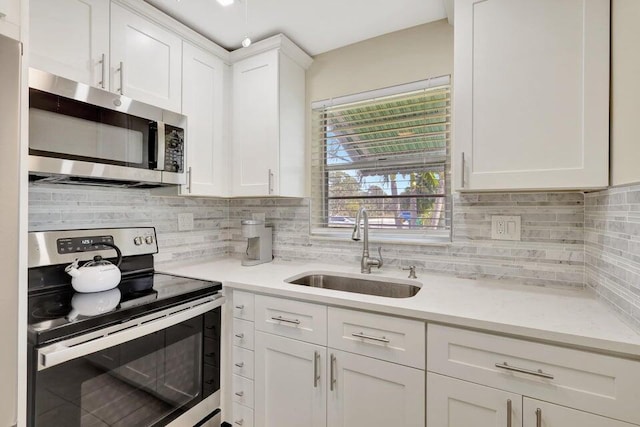 kitchen featuring stainless steel appliances, white cabinetry, tasteful backsplash, and sink