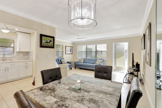 dining area featuring light tile patterned floors, ceiling fan with notable chandelier, ornamental molding, and sink