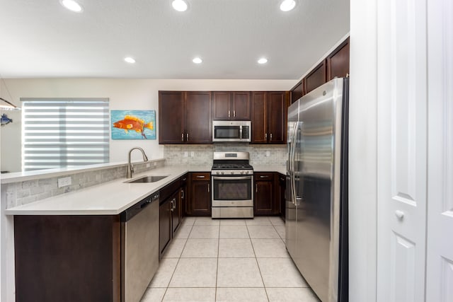 kitchen with appliances with stainless steel finishes, backsplash, dark brown cabinetry, sink, and light tile patterned flooring