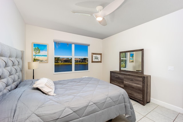 tiled bedroom featuring a water view and ceiling fan