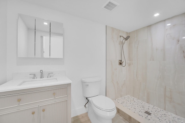 bathroom featuring tiled shower, vanity, and toilet