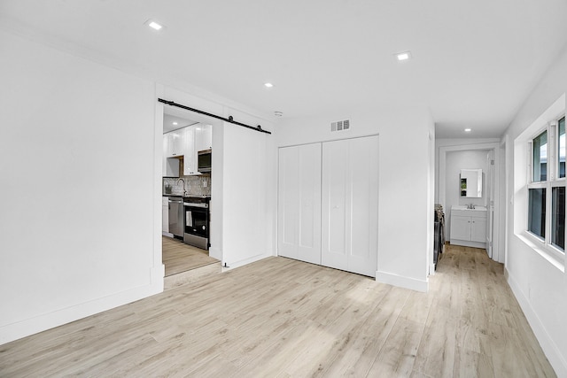 unfurnished living room featuring light wood-type flooring and sink