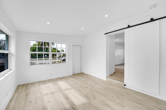 empty room featuring a barn door and light hardwood / wood-style floors