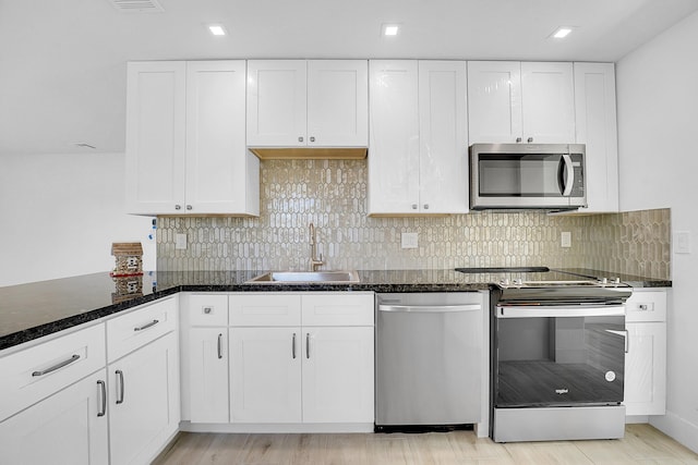 kitchen with white cabinetry, sink, light hardwood / wood-style flooring, decorative backsplash, and appliances with stainless steel finishes