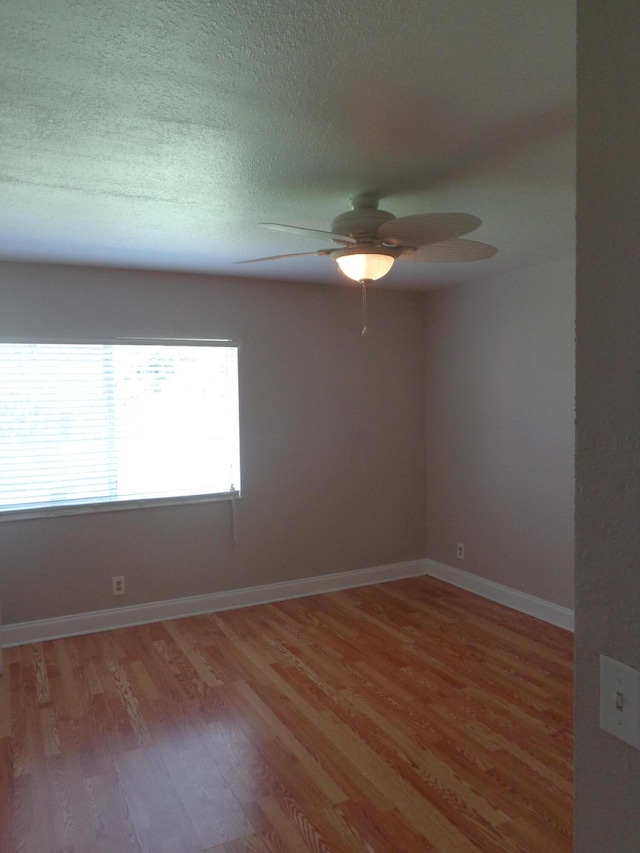 empty room with ceiling fan, wood-type flooring, and a textured ceiling