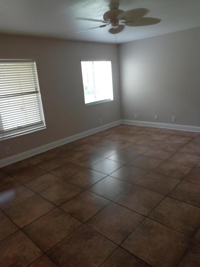 spare room with dark tile patterned flooring and ceiling fan