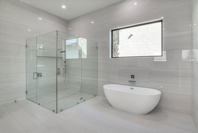18416 Symphony Ct, Jupiter, FL 33458 - full bathroom with a freestanding tub, a shower stall, tile patterned flooring, and tile walls