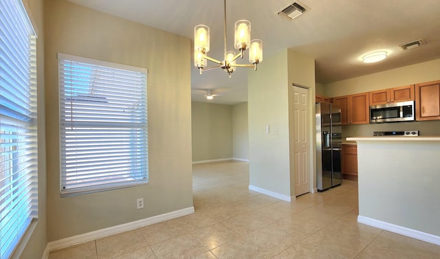 kitchen featuring hanging light fixtures, light tile patterned flooring, stainless steel appliances, and a notable chandelier