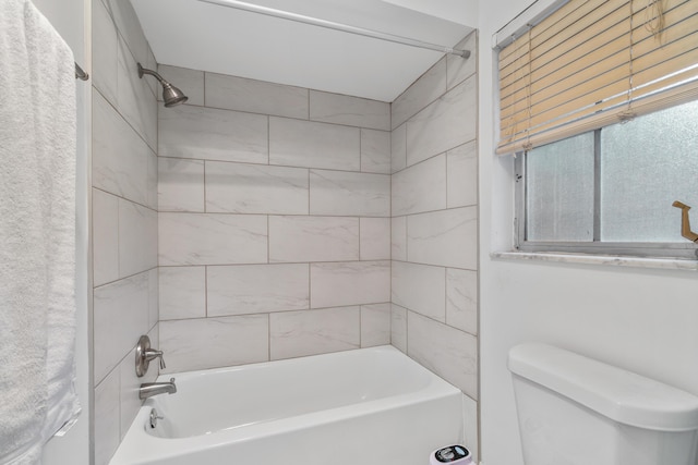 bathroom featuring toilet and tiled shower / bath