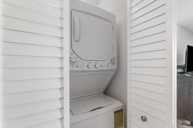 washroom with hardwood / wood-style floors and stacked washer / drying machine