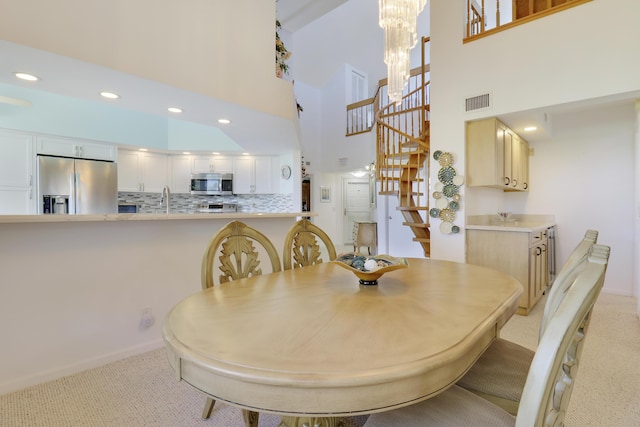 dining room featuring a high ceiling, light colored carpet, a notable chandelier, and sink