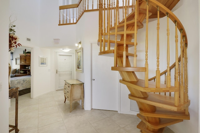 stairway featuring tile patterned flooring and a towering ceiling