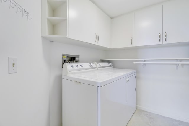 clothes washing area featuring washer and dryer and cabinets