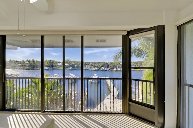 unfurnished sunroom featuring a water view, plenty of natural light, and ceiling fan