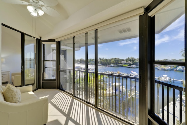 sunroom featuring ceiling fan and a water view