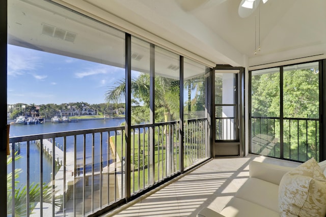 sunroom / solarium with ceiling fan and a water view