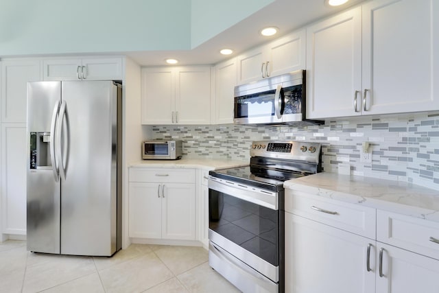 545 Bay Colony Dr N, Juno Beach, FL 33408 - kitchen featuring stainless steel appliances, light tile patterned flooring, white cabinets, tasteful backsplash, and recessed lighting