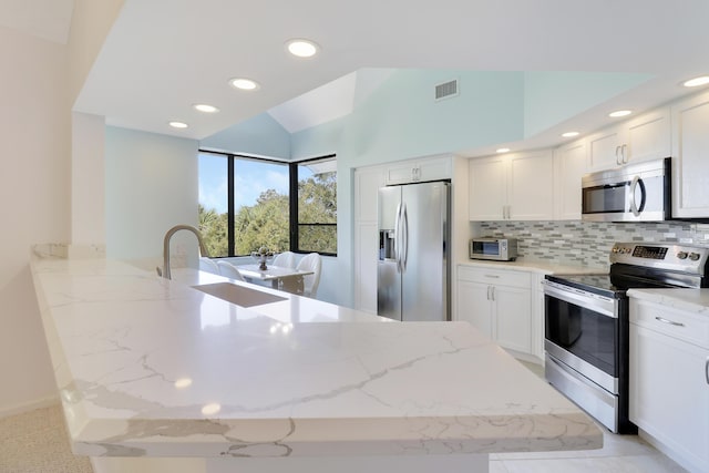 kitchen featuring white cabinets, stainless steel appliances, and light stone countertops