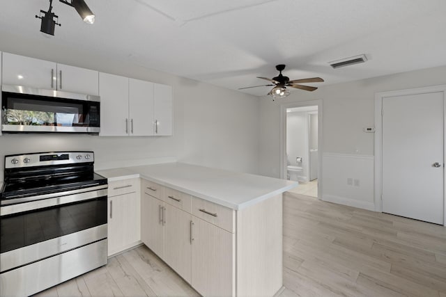 kitchen featuring white cabinets, ceiling fan, appliances with stainless steel finishes, light hardwood / wood-style floors, and kitchen peninsula