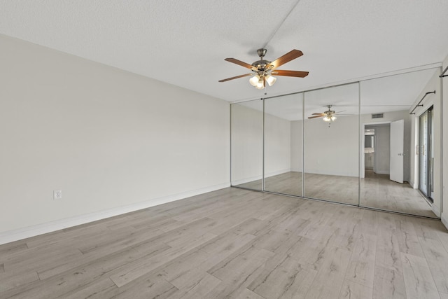 unfurnished bedroom featuring a textured ceiling, a closet, light hardwood / wood-style floors, and ceiling fan