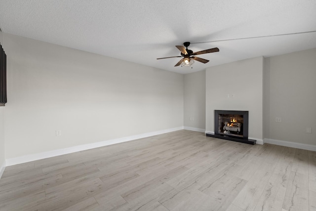 unfurnished living room with a textured ceiling, light hardwood / wood-style flooring, and ceiling fan