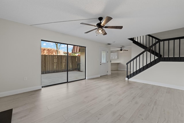 unfurnished living room with ceiling fan, light wood-type flooring, and a textured ceiling