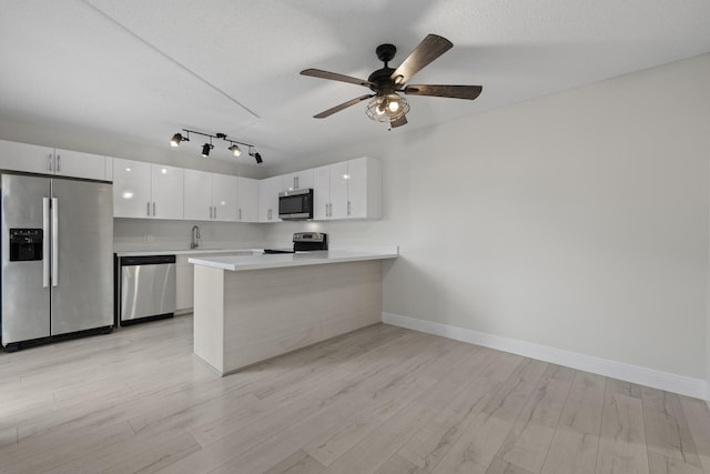 kitchen featuring kitchen peninsula, white cabinetry, light wood-type flooring, and appliances with stainless steel finishes